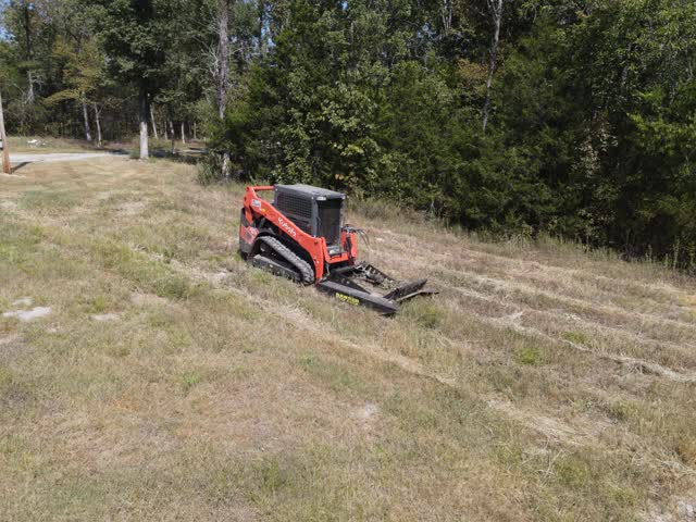Skid-steer brush hog cutting through an overgrown field in Rutherford County, TN